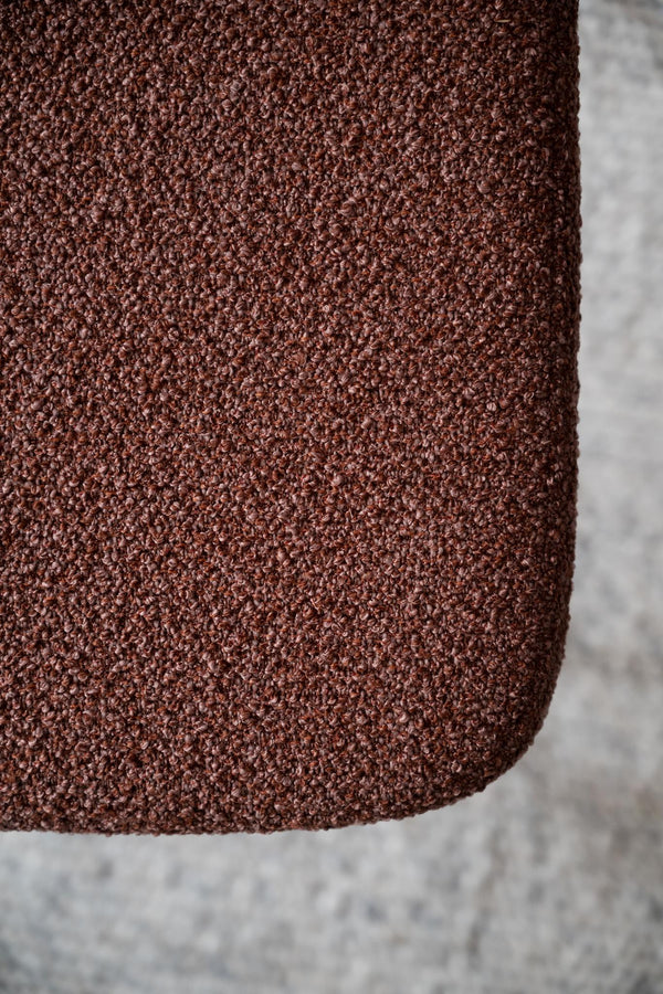 Närbild på rödbrunt bouclé-tyg med texturerad yta och mjuk struktur