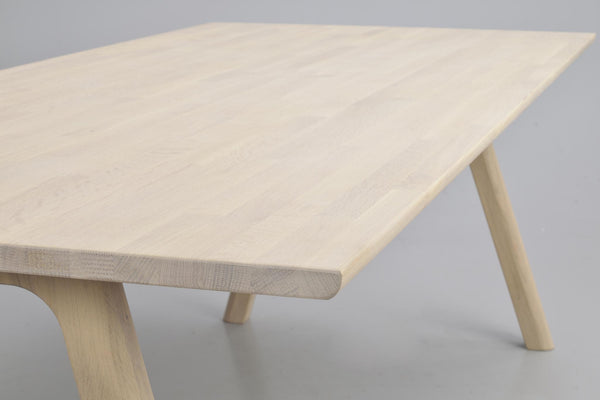 Ljust träbord med rundade hörn och sneda ben i naturlig ek, närbild av bordsskiva och konstruktion
