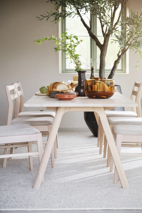 Ljust matbord i trä med matchande stolar och dukade tillbehör i skandinavisk stil