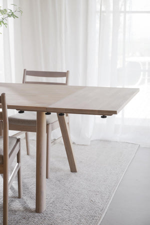 Ljust trämöbelbord med matchande stolar i skandinavisk design på vit matta