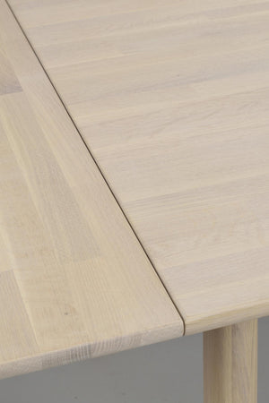 Närbild på ljust träbord med rundad kant och synlig trästruktur, modern skandinavisk design