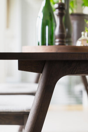 Närbild på mörkbrun träbordsben med sned vinkel och synlig trästruktur, modern skandinavisk design