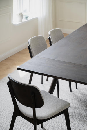 Matgrupp med grå stolar och svartbetsad träram i minimalistisk skandinavisk design