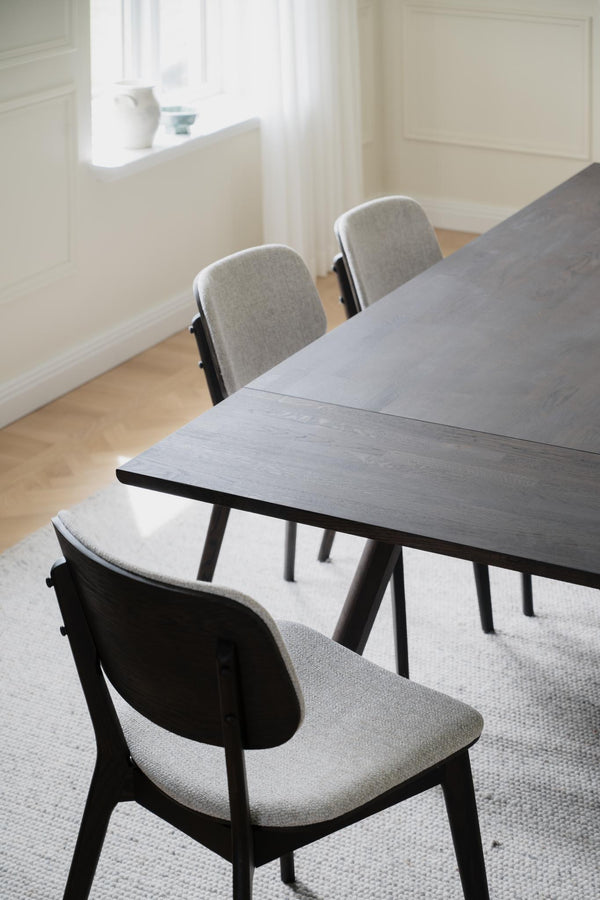 Matgrupp med grå stolar och svartbetsad träram i minimalistisk skandinavisk design