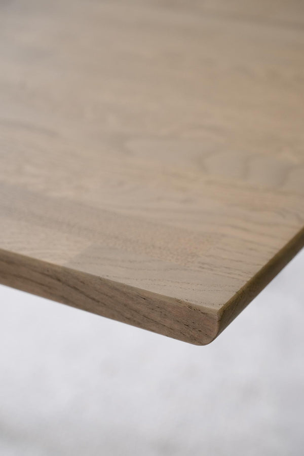 Närbild på hörn av träskiva med synlig trästruktur och avfasad kant i ljust trä