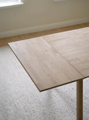 Ljust trä matbord med utdragsskiva i ek, modern skandinavisk design på ljus matta