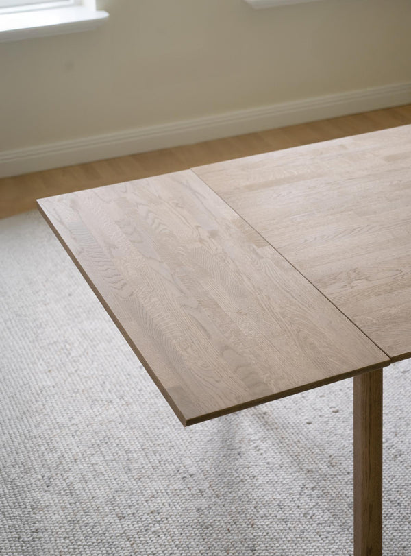 Ljust trä matbord med utdragsskiva i ek, modern skandinavisk design på ljus matta