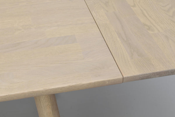 Ljust trä matbord med synlig fog och rundad kant, närbild på bordsskiva och ben i ekfanér