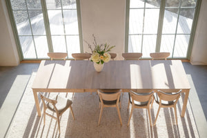 Matbord i ljust trä med matchande stolar i ljust matrum med stora fönster och vit matta