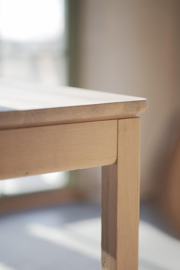 Närbild på hörn av träbord i ljus ek med synlig trästruktur och snickeridetaljer