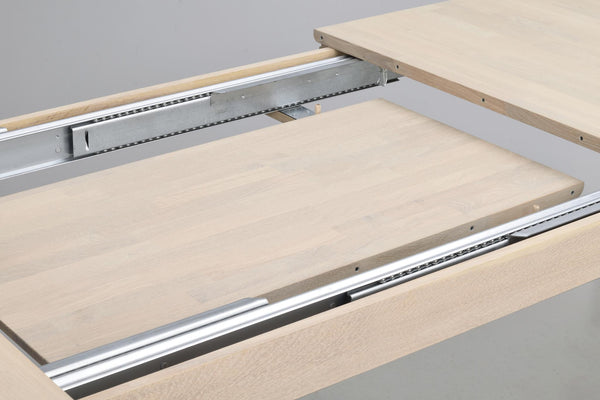 Utdragbar bordsskiva med metallskenor som visar förlängningsfunktion på träbord