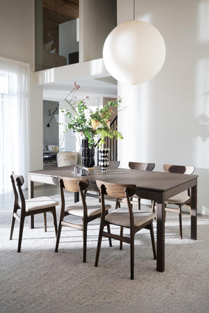 Matbord i grått med stolar i trä i modern matsal med vit klotlampa och växter som dekoration
