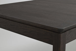 Närbild på mörkbetsad träbordskiva med rundad kant och synlig trästruktur