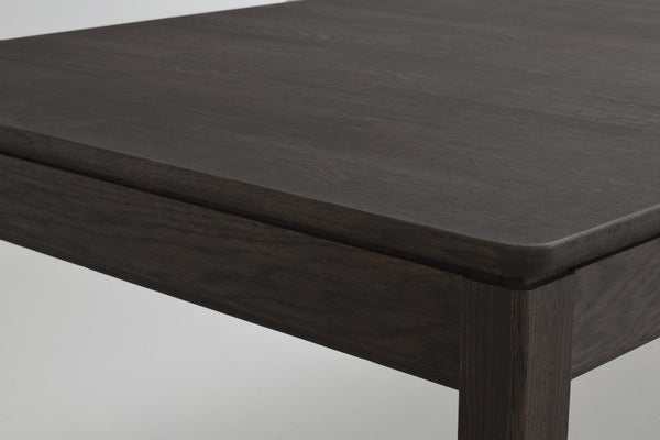 Närbild på mörkbetsad träbordskiva med rundad kant och synlig trästruktur