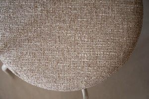 Närbild på beige stol med linneliknande klädsel i melerad vävd textil