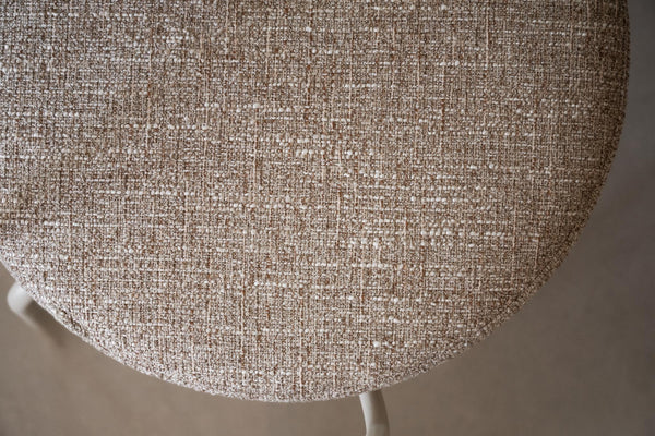 Närbild på beige stol med linneliknande klädsel i melerad vävd textil