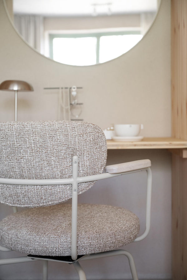 Grå melerad fåtölj med vita armstöd vid skrivbord i ljust skandinaviskt hem