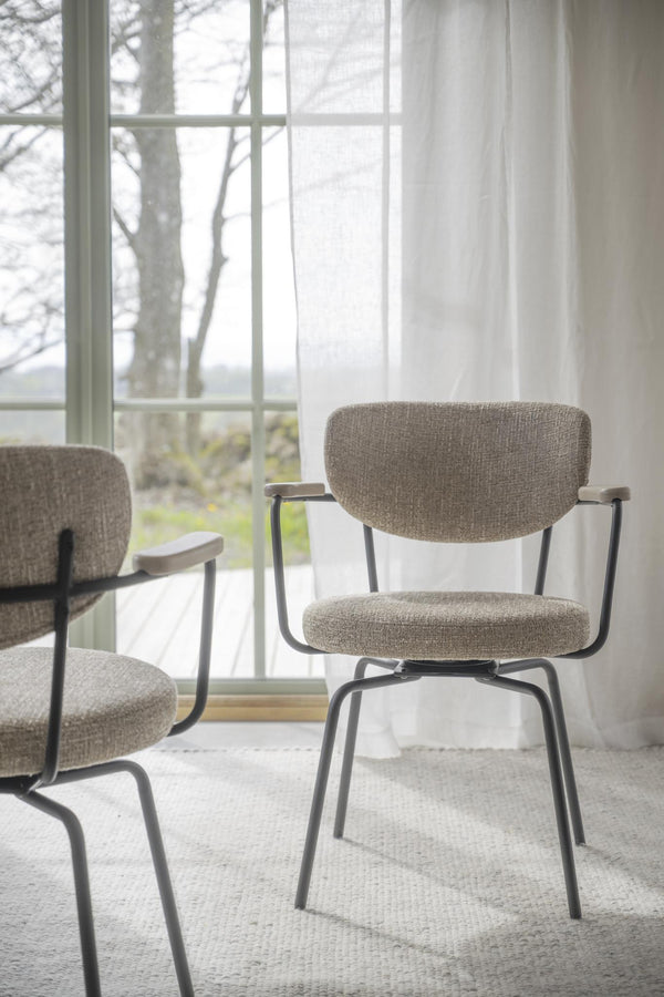 Stol med grå klädsel och svarta metallben vid fönster med utsikt
