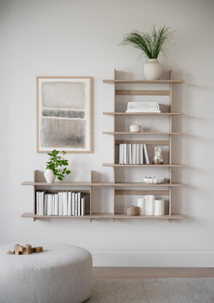 Väggmonterad bokhylla i ljust trä med böcker och dekorationer i minimalistisk skandinavisk stil