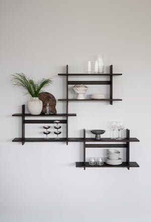 Moderna vägghyllor i mörkt trä med asymmetrisk design, dekorerade med vaser, glas och keramik mot ljus vägg