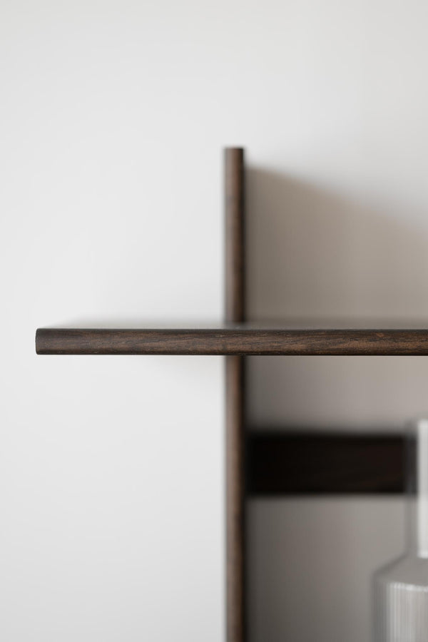 Närbild av mörkbrun trälist i minimalistisk skandinavisk design mot vit vägg