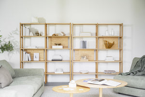 Ljus bokhylla i trä med öppna fack, dekorerad med böcker och prydnadsföremål i modernt vardagsrum