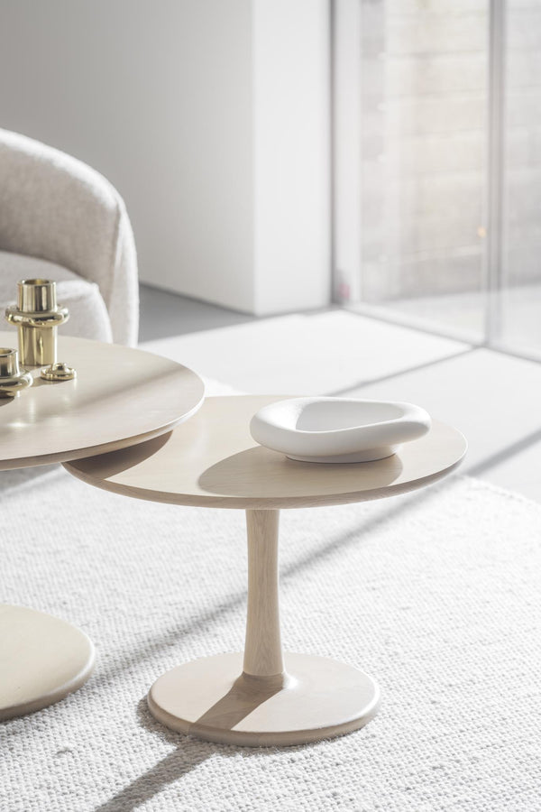 Runda soffbord i ljust trä med vit keramikskål och mässingslampa i minimalistisk vardagsrumsinredning