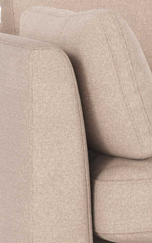 Beige stoppad soffa med mjuka kuddar och textilklädsel i närbild