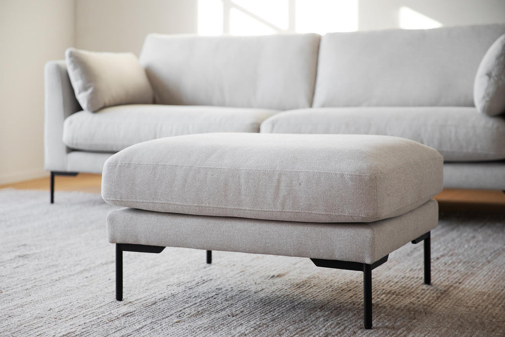 Beige sittpuff med svarta metallben, modern design med mjuk klädsel och raka linjer