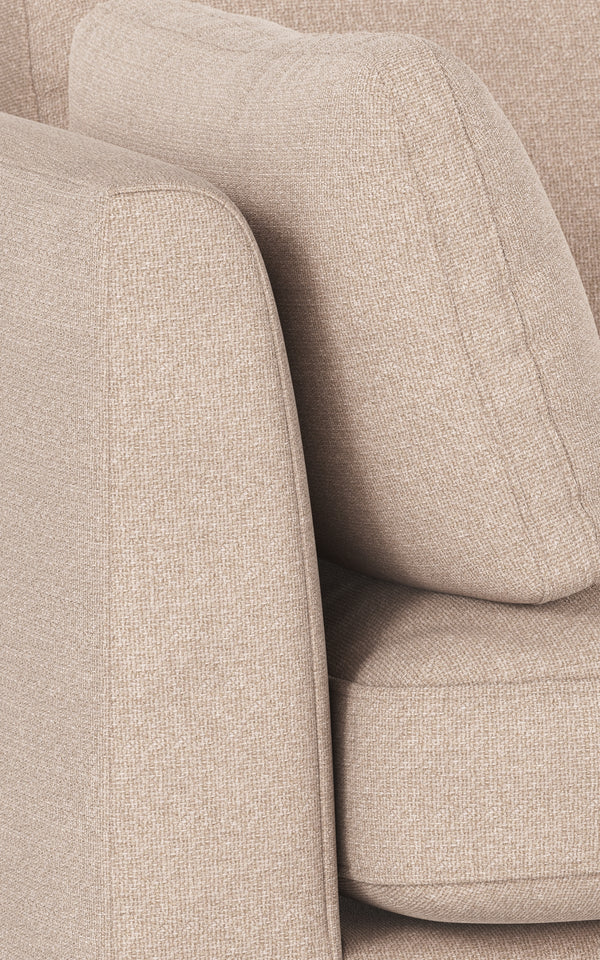Beige stoppad fåtölj med mjuka rundade former och strutformad rygg i linnelikanande tyg