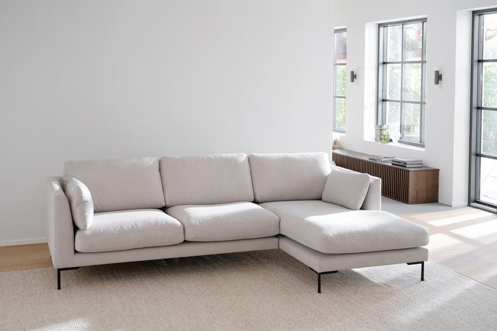 Beige soffa med schäslong och svarta metallben, modern design med tre sittplatser