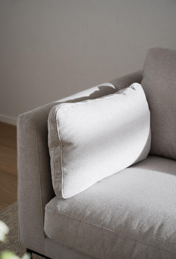 Grå soffa med vit kudde i linnetyg, närbild på sittdel och armstöd