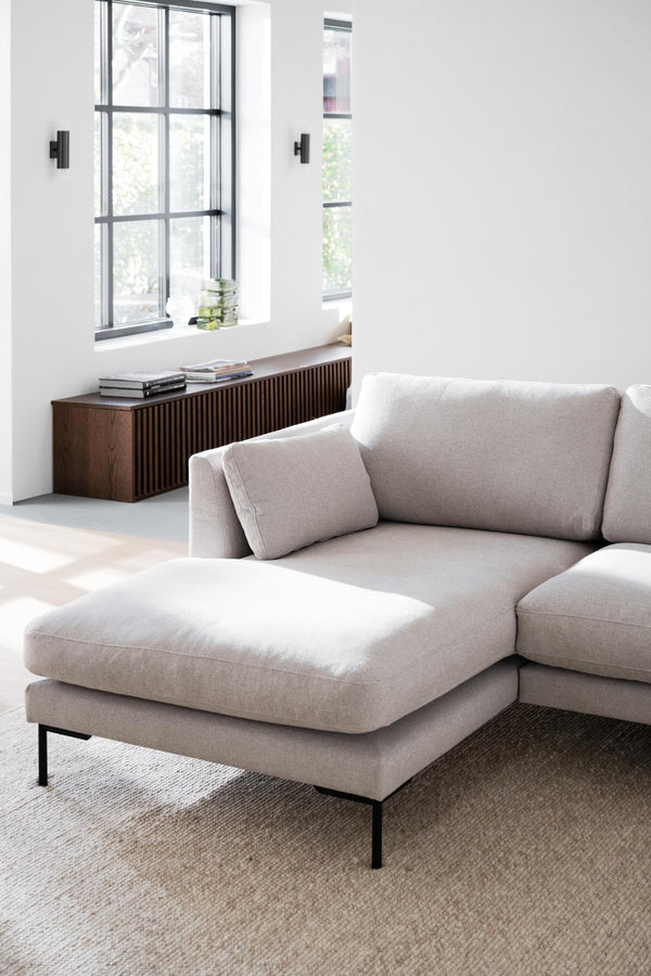 Beige sektionssoffa med schäslong i modernt vardagsrum med vita väggar och mörkt träskåp