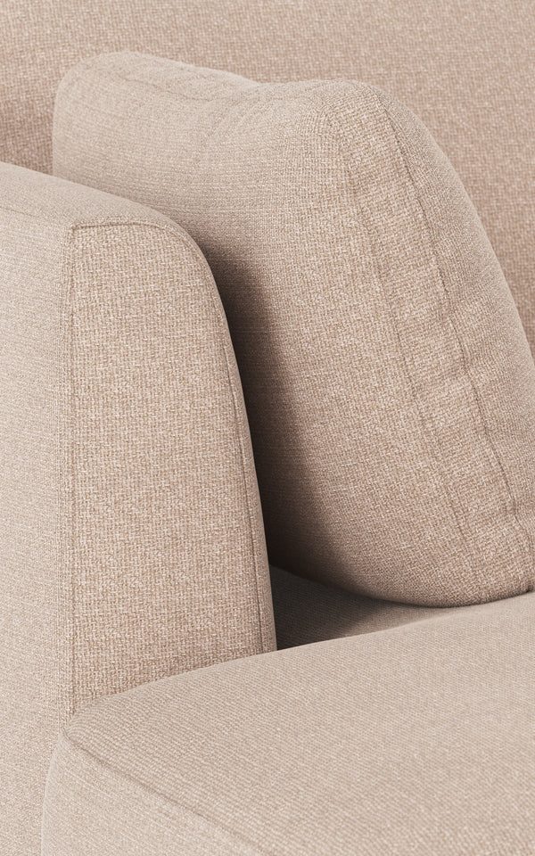 Beige stoppad soffa med mjuka kurviga former och linnelikt tyg i närbild