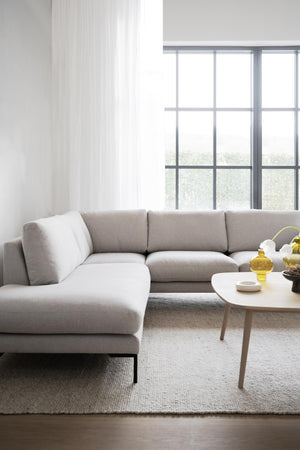 Ljusgrå hörnsoffa i modernt vardagsrum med runda soffbord och stora fönster