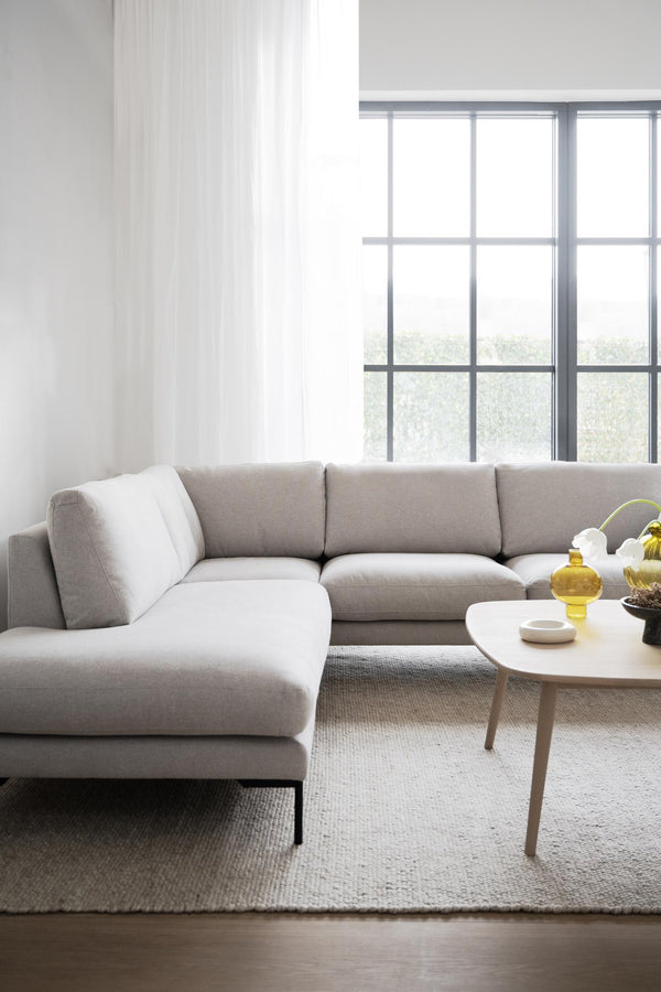 Ljusgrå hörnsoffa i modernt vardagsrum med runda soffbord och stora fönster