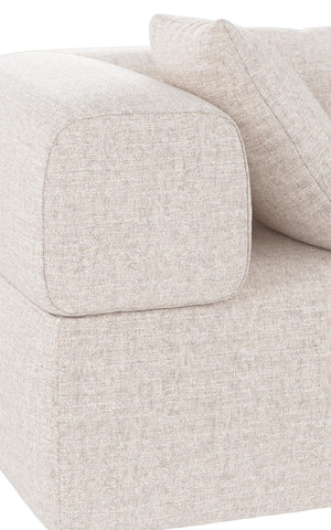 Beige soffa med mjuka kuddar och rundade armstöd i ljust tyg