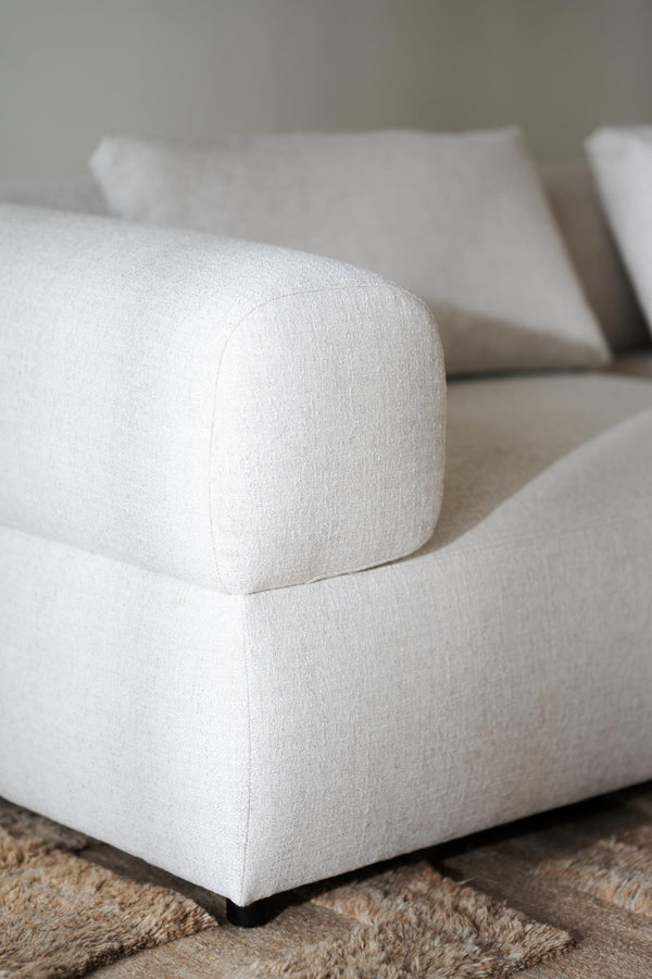 Vit soffa med rundad armstöd i bouclétyg på beige matta, närbild av hörn och detaljer