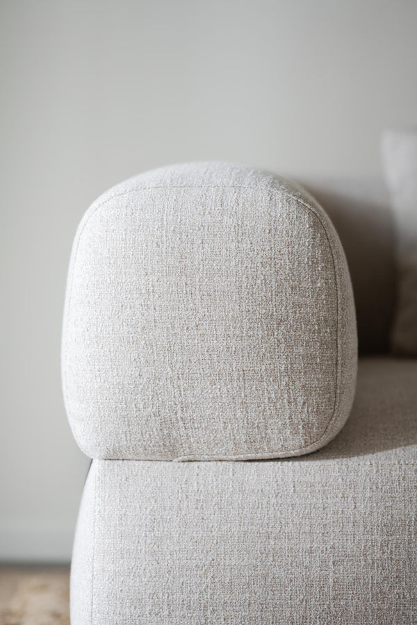 Närbild av beige fåtölj med rundade former och mjuk klädsel i ljust tyg