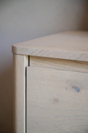 Närbildsdetalj av ljust träskåp med synlig trästruktur och sarg i massiv ek
