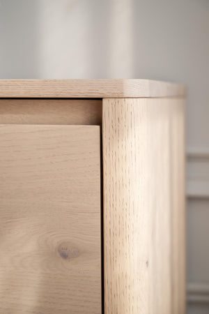 Närbild på hörn av sängbord i ljus ek med synlig trästruktur och låda
