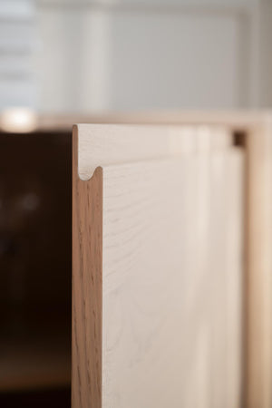 Närbild av ljus träkant med fräst spår och synlig trästruktur på möbel eller lådfronter