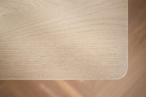 Närbild av ljus ekfanér bordsskiva med naturlig trästruktur och rundad kant