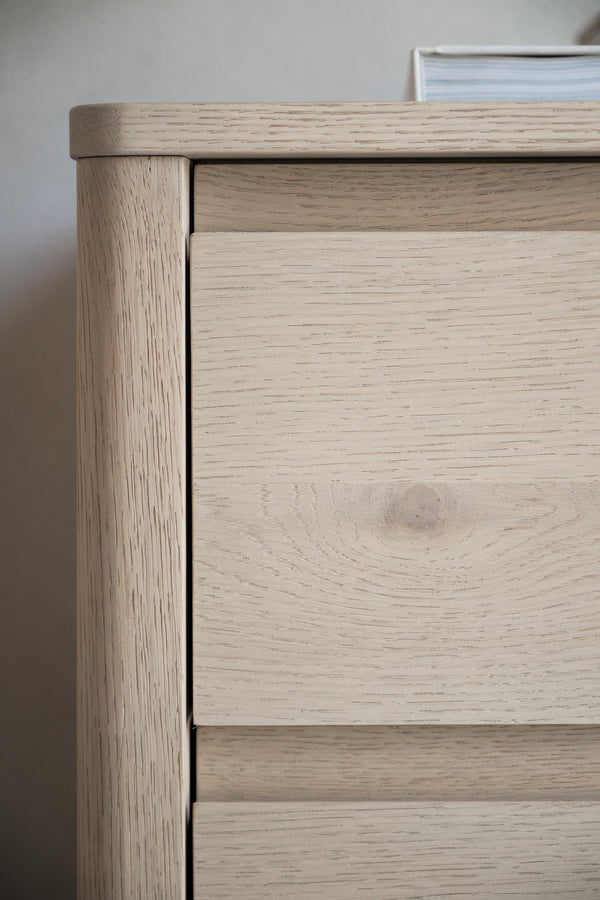 Närbildsdetalj av ljus ekbyrå med synlig trästruktur och diskreta handtag på lådorna