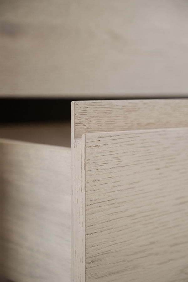 Närbild på hörn av vit låda eller byrå med synlig trästruktur och falsad kant