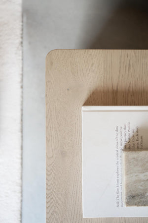 Ljus ekram i trä med synlig trästruktur runt inramad text, närbild av hörn och snickerier