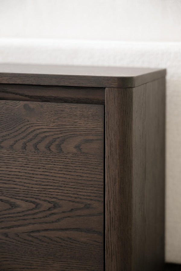 Närbildsdetalj av mörkbrun byrå i massiv ek med synlig trästruktur och lådor