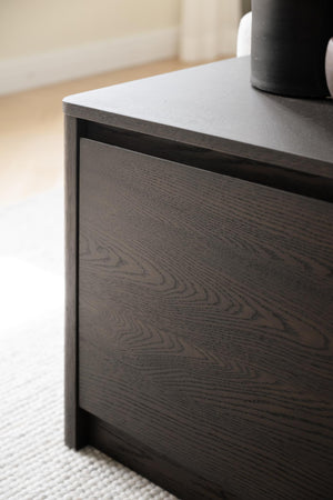 Mörkbrun sängbord med synlig träådring och skjutlåda, closeup på modern skandinavisk design