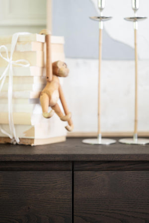 Dekorativa ljusstakar och presentförpackning med ängelfigur på mörk träkommod