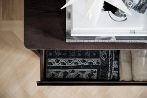 Öppen låda under skrivbord med vikt textil och dekorativt tyg i svartvitt mönster